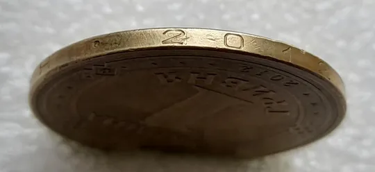 (4679) 1 гривня 2012 різновид викрошки у першій цифрі "2" слова "2012" на гурті (1 гривна 2012 брак) З аукціону